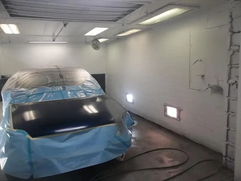 Car masked off with a freshly painted hood in the paint booth