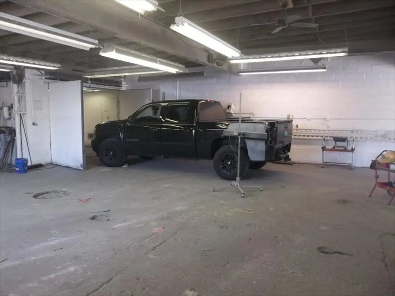 Black pickup truck with a primed rear panel inside the shop