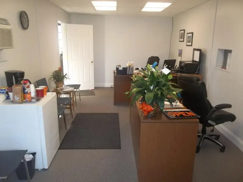 Front office with chairs, a coffee station, and an Open sign on the desk